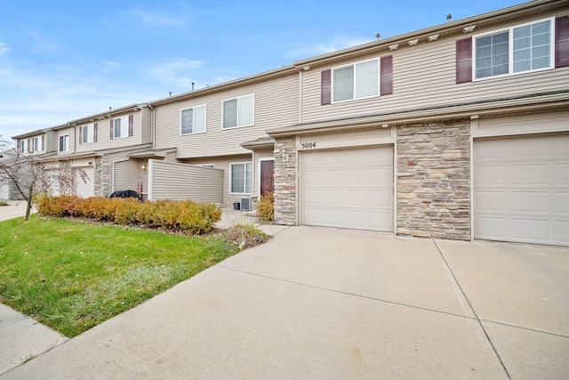 multi unit property with a front lawn, central AC unit, and a garage