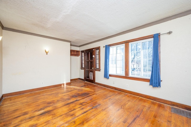 spare room with crown molding, hardwood / wood-style floors, and a textured ceiling