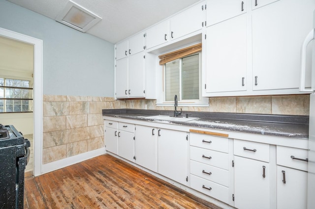 kitchen with sink, black range with electric cooktop, dark hardwood / wood-style flooring, a textured ceiling, and white cabinets