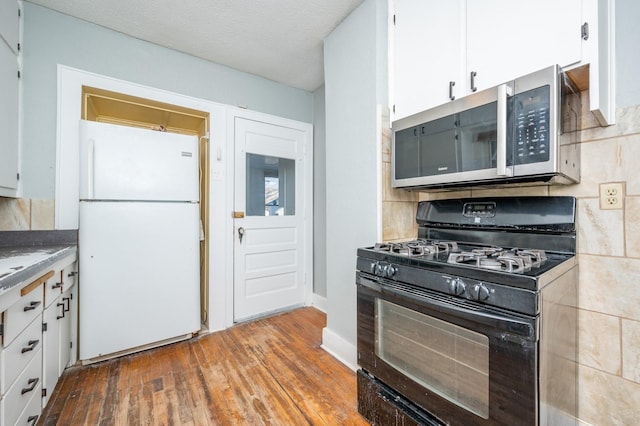 kitchen featuring white cabinetry, black range with gas stovetop, backsplash, white fridge, and light hardwood / wood-style floors