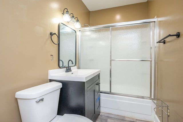 full bathroom with shower / bath combination with glass door, hardwood / wood-style floors, vanity, and toilet