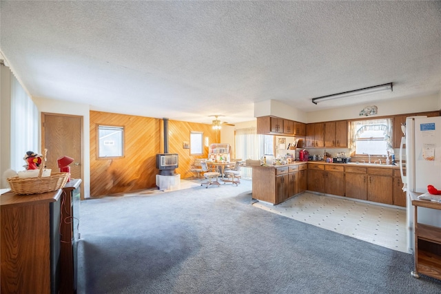 kitchen with ceiling fan, sink, kitchen peninsula, a textured ceiling, and wooden walls