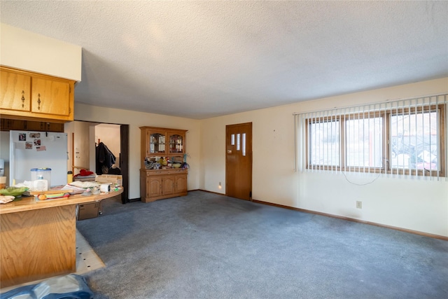 kitchen with a textured ceiling, white fridge, and light colored carpet