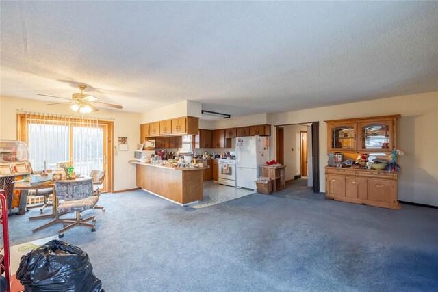 kitchen featuring ceiling fan, dark colored carpet, kitchen peninsula, a textured ceiling, and white appliances