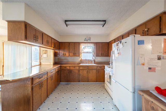 kitchen featuring a textured ceiling, white appliances, and sink