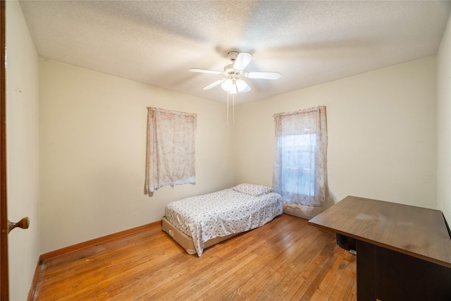 bedroom with hardwood / wood-style flooring, ceiling fan, and a textured ceiling