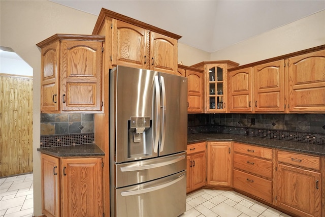 kitchen with decorative backsplash, stainless steel fridge, light tile patterned floors, and dark stone counters