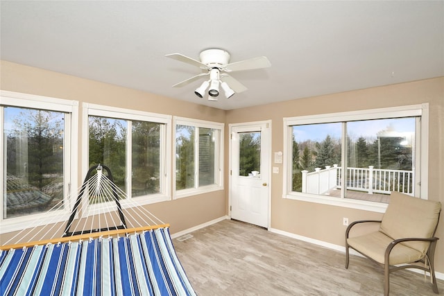 unfurnished sunroom with ceiling fan