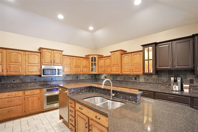 kitchen featuring backsplash, stainless steel appliances, vaulted ceiling, sink, and dark stone countertops