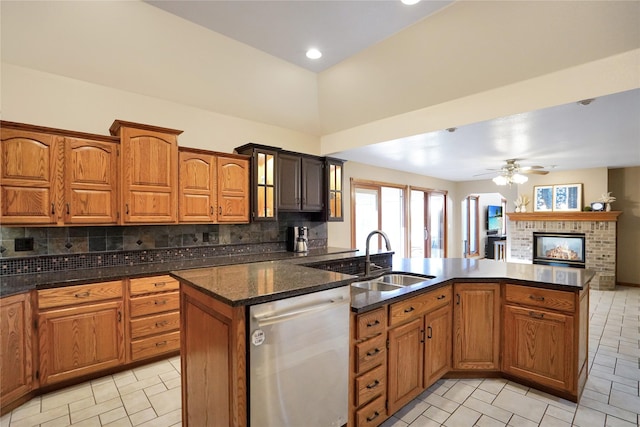 kitchen featuring dark stone counters, sink, stainless steel dishwasher, ceiling fan, and tasteful backsplash