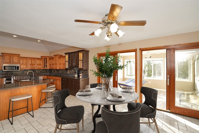 tiled dining space featuring ceiling fan, lofted ceiling, and sink