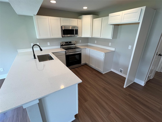 kitchen featuring sink, appliances with stainless steel finishes, white cabinetry, dark hardwood / wood-style floors, and kitchen peninsula