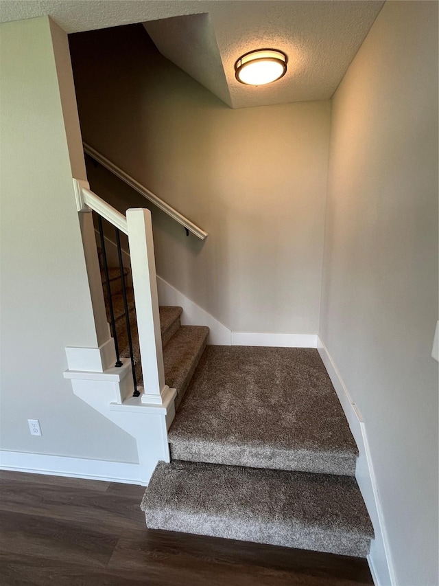 stairway featuring hardwood / wood-style floors and a textured ceiling