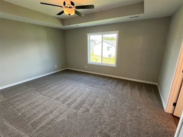 carpeted empty room featuring a tray ceiling and ceiling fan