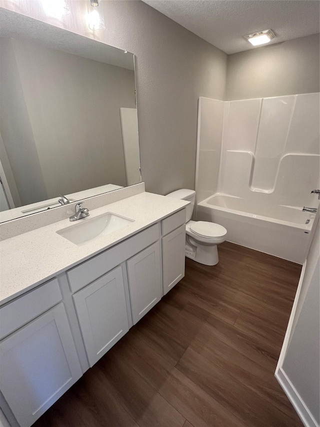 full bathroom with shower / tub combination, hardwood / wood-style floors, vanity, a textured ceiling, and toilet