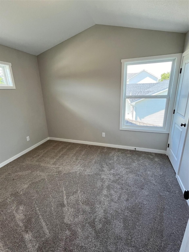 unfurnished room with dark carpet and vaulted ceiling