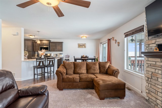 living room featuring hardwood / wood-style flooring, ceiling fan, and a fireplace