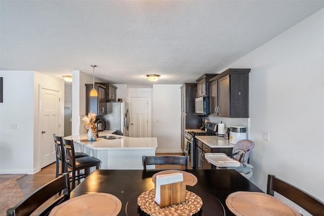 kitchen featuring kitchen peninsula, appliances with stainless steel finishes, a textured ceiling, sink, and pendant lighting