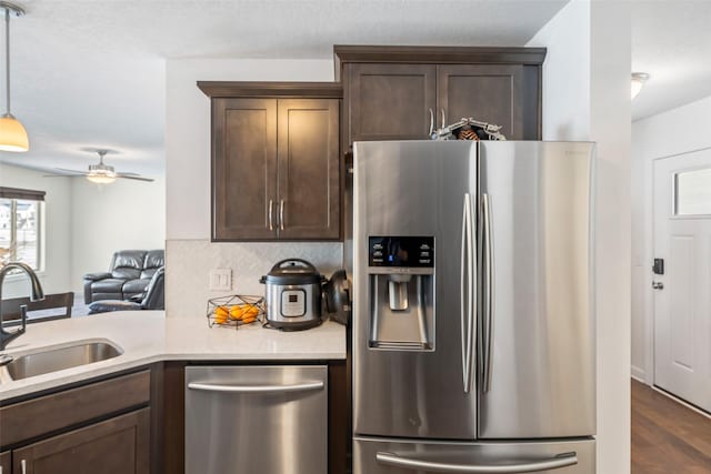 kitchen featuring pendant lighting, sink, appliances with stainless steel finishes, dark hardwood / wood-style flooring, and dark brown cabinetry