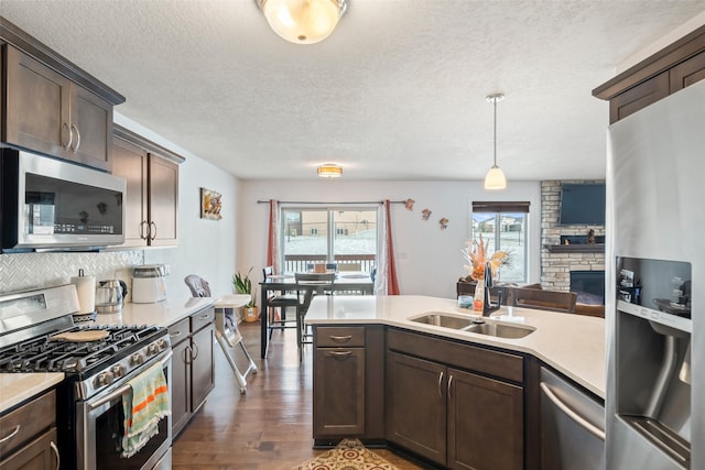 kitchen with appliances with stainless steel finishes, dark hardwood / wood-style flooring, decorative light fixtures, and a healthy amount of sunlight