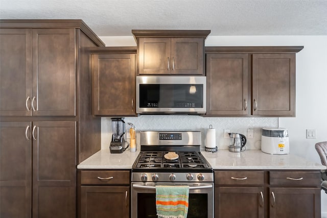 kitchen with dark brown cabinetry, light stone countertops, and appliances with stainless steel finishes