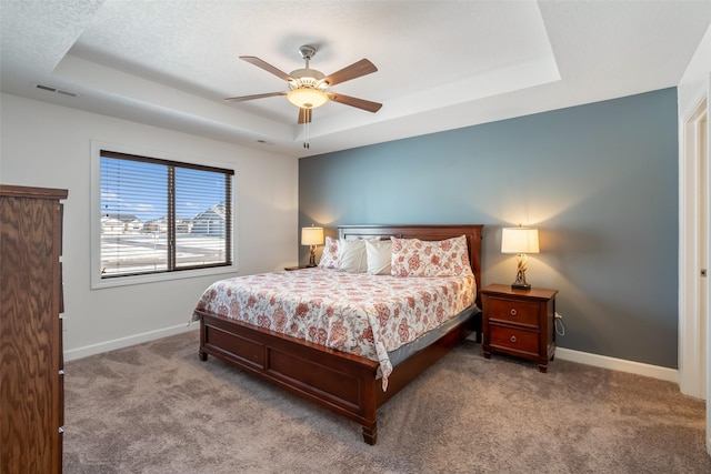 carpeted bedroom with a tray ceiling and ceiling fan