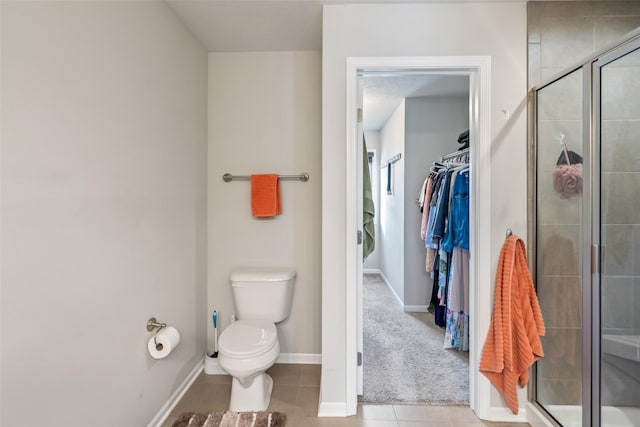 bathroom featuring toilet, tile patterned floors, and a shower with shower door