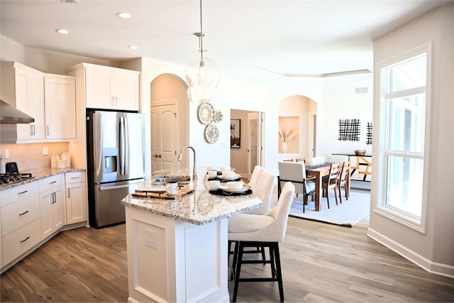 kitchen featuring a center island with sink, plenty of natural light, white cabinetry, and stainless steel appliances