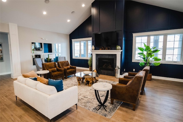 living room featuring a fireplace, light hardwood / wood-style flooring, and high vaulted ceiling