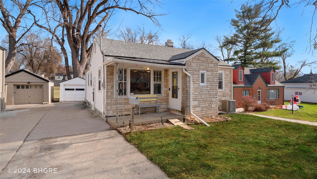 view of front of house featuring cooling unit, a garage, an outdoor structure, and a front yard