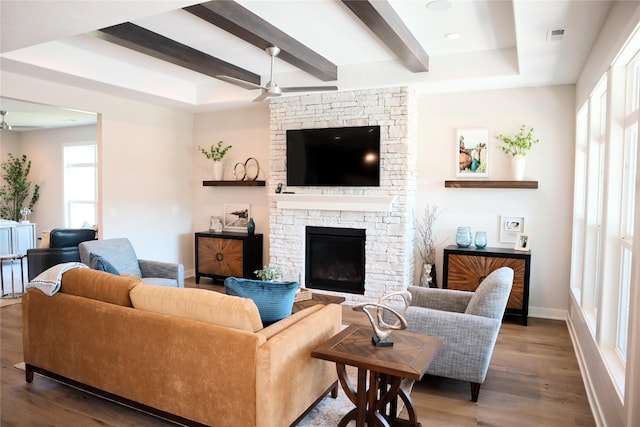 living room featuring hardwood / wood-style flooring, ceiling fan, a fireplace, a tray ceiling, and beam ceiling