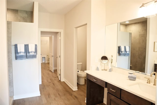 bathroom featuring hardwood / wood-style flooring, vanity, toilet, and a tile shower