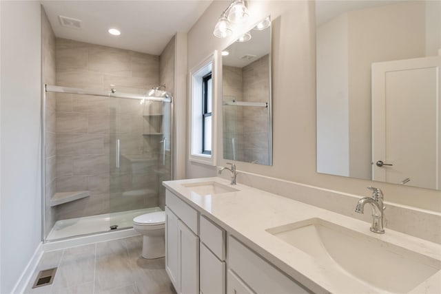 bathroom featuring tile patterned flooring, vanity, toilet, and a shower with door