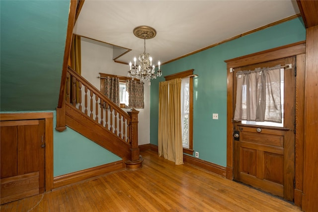 foyer featuring a notable chandelier, light wood-type flooring, and ornamental molding