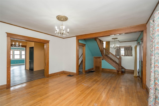 spare room featuring hardwood / wood-style flooring, crown molding, and a chandelier