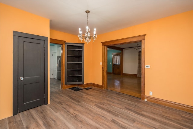 unfurnished dining area featuring a notable chandelier and wood-type flooring