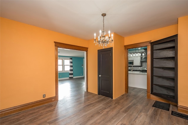 unfurnished dining area with dark hardwood / wood-style flooring and a notable chandelier