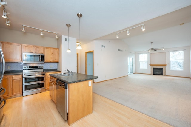 kitchen featuring appliances with stainless steel finishes, ceiling fan, pendant lighting, lofted ceiling, and an island with sink