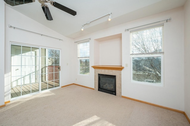 unfurnished living room with carpet flooring, a tile fireplace, ceiling fan, rail lighting, and vaulted ceiling