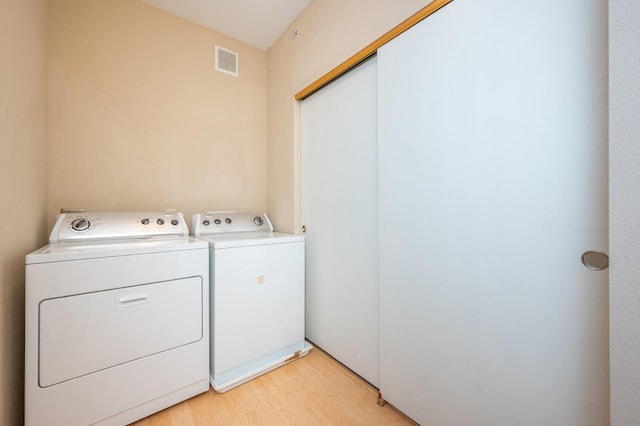 laundry area featuring washer and clothes dryer and light hardwood / wood-style flooring