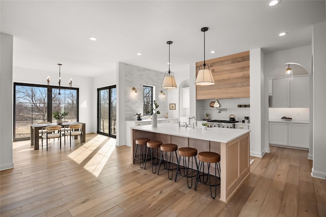 kitchen with a spacious island, light hardwood / wood-style flooring, a kitchen breakfast bar, and decorative light fixtures