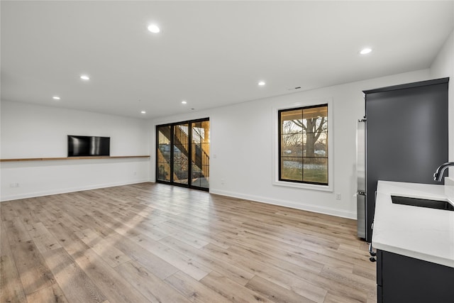 unfurnished living room with sink and light hardwood / wood-style floors