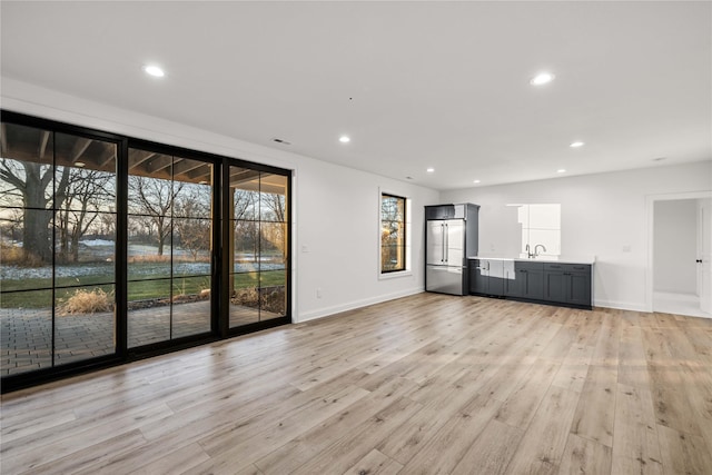 unfurnished living room featuring sink and light hardwood / wood-style flooring