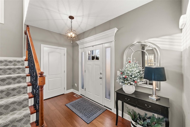 foyer entrance featuring dark wood-type flooring and an inviting chandelier