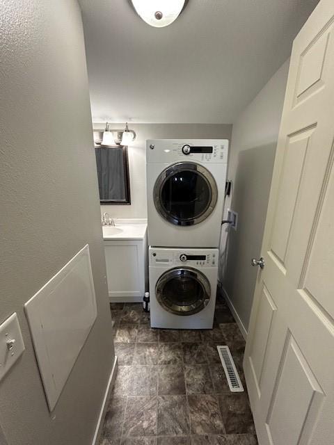 laundry area featuring sink and stacked washing maching and dryer