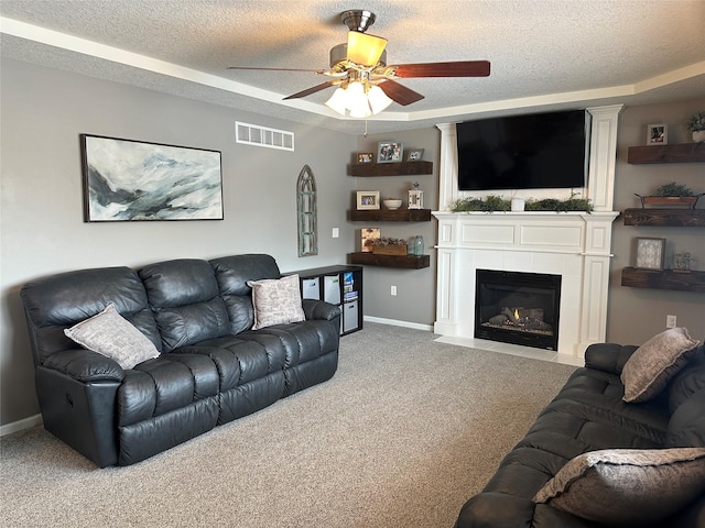 carpeted living room with a tile fireplace, a textured ceiling, and a tray ceiling