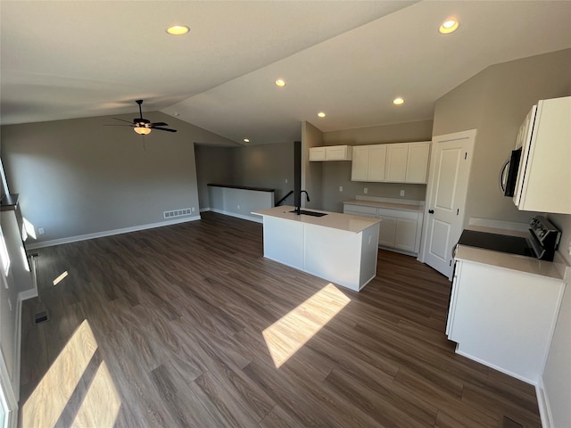 kitchen featuring dark wood-type flooring, lofted ceiling, sink, white cabinetry, and a center island with sink