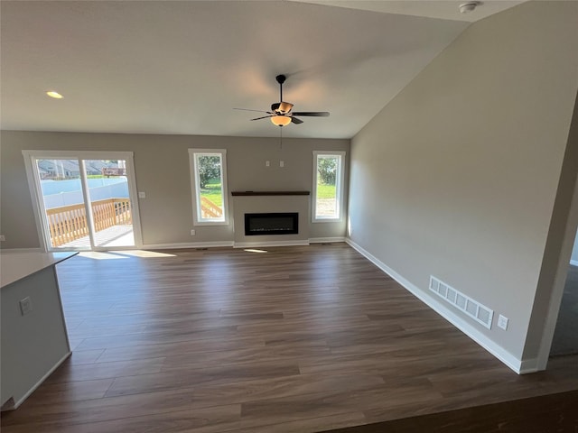 unfurnished living room featuring ceiling fan, dark hardwood / wood-style floors, and vaulted ceiling