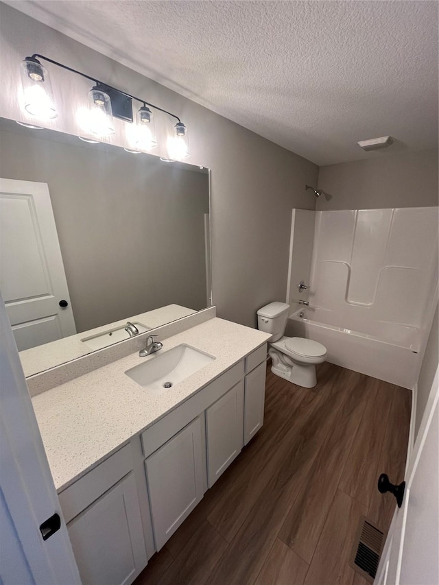 full bathroom featuring  shower combination, hardwood / wood-style floors, a textured ceiling, and toilet