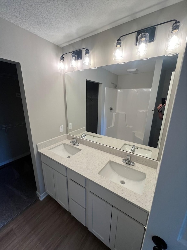 bathroom featuring walk in shower, wood-type flooring, a textured ceiling, and vanity